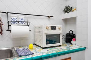 Eine Küche mit Backofen, Spüle, Küchenpapierrolle und einer kleinen Pflanze.