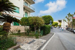 Straßenansicht mit einem Gebäude, Balkonen, einem Bürgersteig und geparkten Autos.