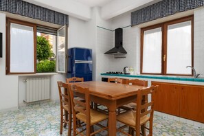Eine kompakte Küche mit Esstisch, Stühlen, Kühlschrank und Herd.