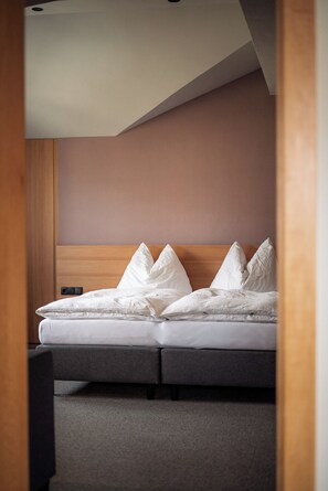 A bedroom with a bed, a wooden headboard, and a carpeted floor. - 90m² Apartment Emilia up to 8 pers. - Julius Apartments. (Hofmark)