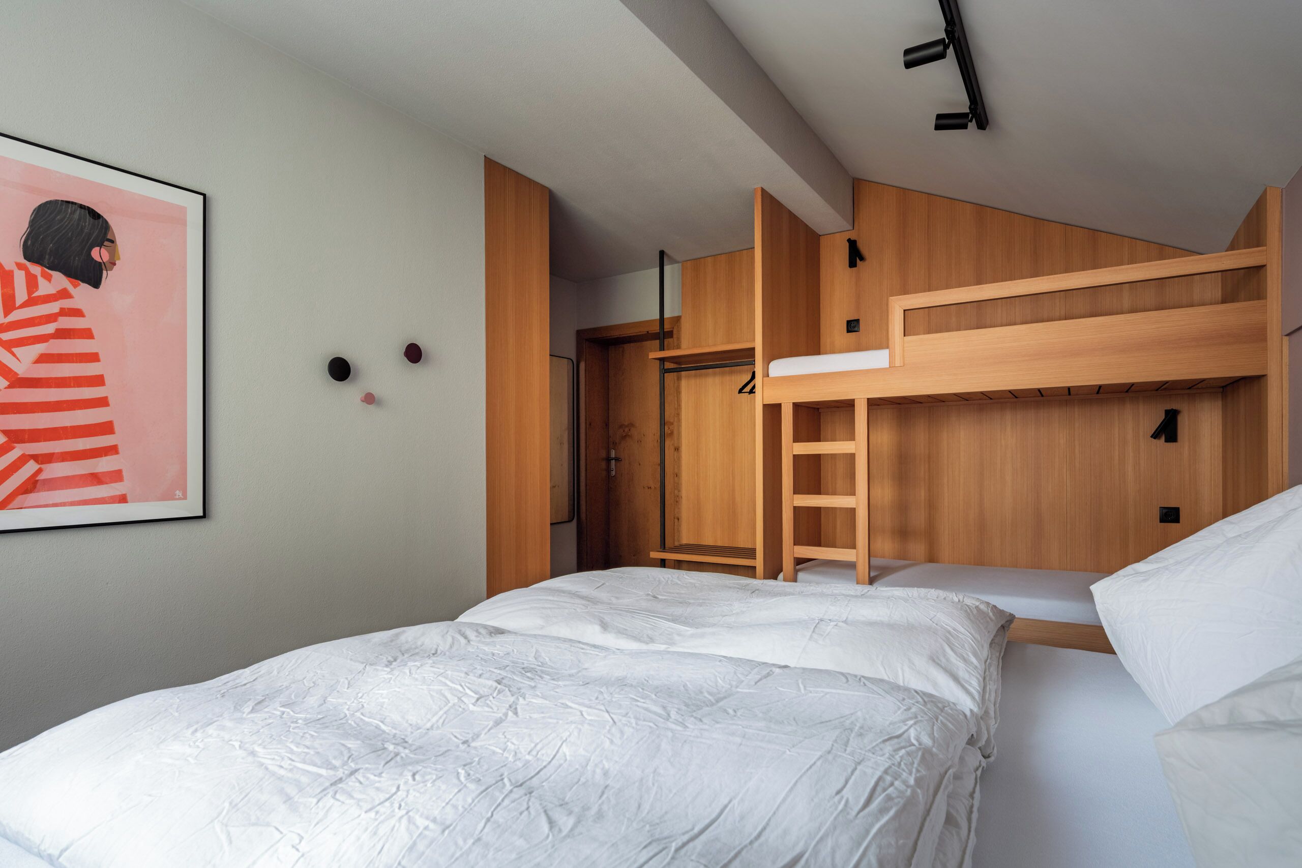 A bunk bed room with a ladder, a framed picture on the wall, and a closet.