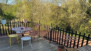 A wooden deck with a table and chairs, surrounded by a wooden fence and greenery. - Le vieux noyer - Room Two - In the heart of the Morvan countryside. (Montlay-en-Auxois)