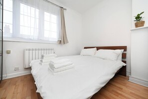 A bedroom with a bed, a radiator, a window with curtains, and a plant on a shelf. - Full House 2 Bedrooms, 2 Bathrooms, Near Tube st (London)