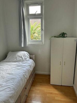 A bedroom with a bed, a wardrobe, a window with curtains, and a view of greenery outside. - Full House 2 Bedrooms, 2 Bathrooms, Near Tube st (London)