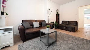 Ein Wohnzimmer mit einem braunen Ledersofa, einem grauen Couchtisch und einer weißen Kommode.