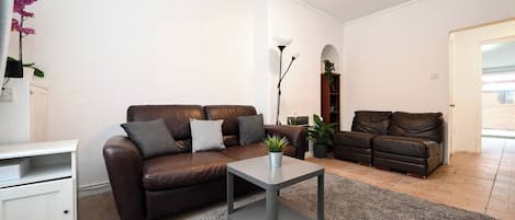 Una sala de estar con un sofá de cuero marrón, una mesa de centro gris y un armario blanco.