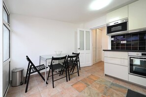 A modern kitchen with white cabinets, a black countertop, and a dining area with a table and chairs. - Full House 2 Bedrooms, 2 Bathrooms, Near Tube st (London)