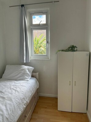 A bedroom with a bed, a window with curtains, a radiator, and a wardrobe. - Full House 2 Bedrooms, 2 Bathrooms, Near Tube st (London)
