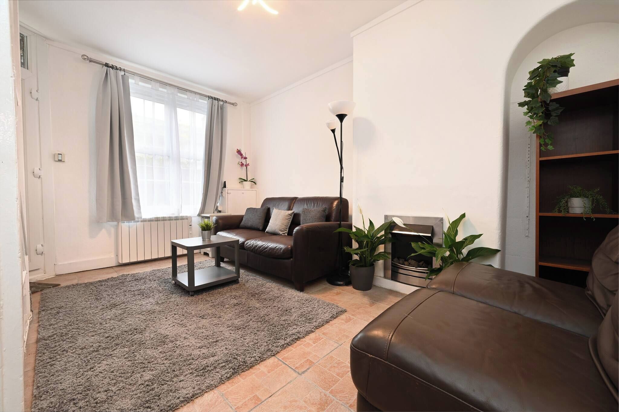 A living room with a sofa, a coffee table, a floor lamp, and a bookshelf.