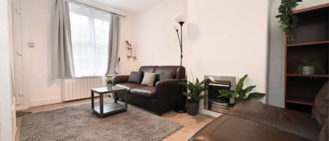 A living room with a sofa, a coffee table, a floor lamp, and a bookshelf.