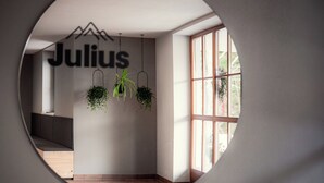 A modern interior with a circular window, a wall-mounted sign reading 'Julius,' and hanging plants. - Family room Markus in Wagrain up to 3 pers - Julius Appartements (Hofmark)