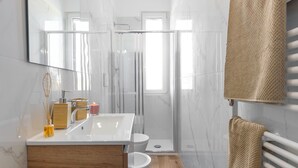 Ein modernes Badezimmer mit einer Duschkabine aus Glas, einem Holzbadezimmer, einem weißen Waschbecken und einem großen Spiegel.