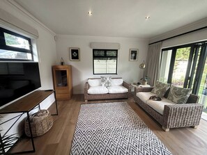 Ein Wohnzimmer mit einer Couch, einem Couchtisch, einem Fernseher und einem großen Fenster.