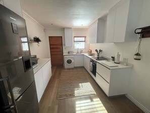 Eine moderne Küche mit Edelstahl-Kühlschrank, Waschmaschine und Spüle.