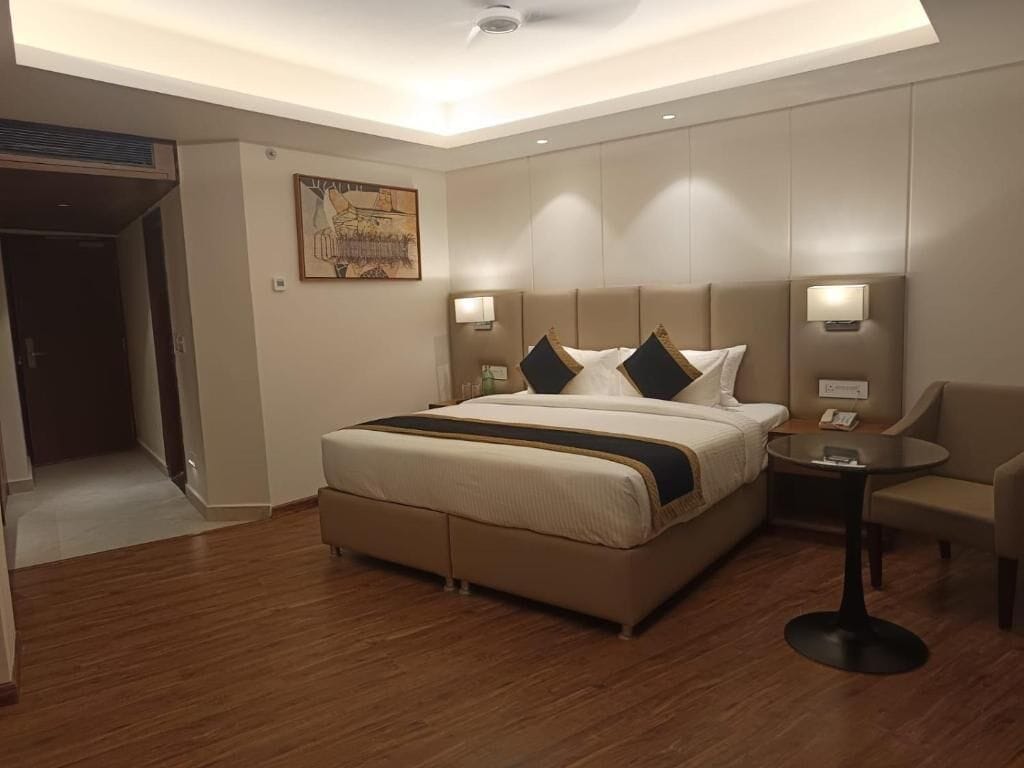 Una habitación de hotel con una cama, lámparas de noche, una mesita y una silla.