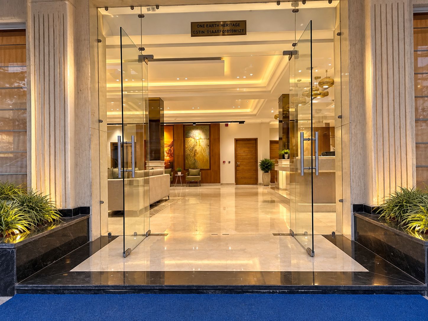 A hotel lobby with a reception desk, seating area, and a large artwork on the wall.