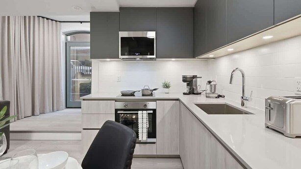 Una cucina moderna con forno integrato, microonde, lavello e tostapane.