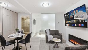 Un soggiorno moderno con camino, TV a parete e zona pranzo con tavolo rotondo e sedie.