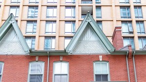 Un edificio a due piani in mattoni rossi con un tendaggio verde, una scala in legno e un cancello nero.