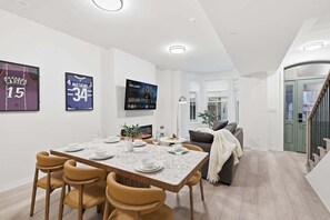 Un espace repas moderne avec une table en marbre, des chaises en cuir et des maillots de sport accrochés au mur.