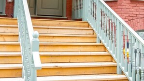 Una escalera con barandilla azul claro que lleva a una puerta marcada con el número 16.