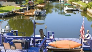 A marina with boats docked, a small dock with a table and chairs, and a flag. - WATERFRONT at Weeki Wachee w/heated swimming pool, docks, Kayaks & elevator (Spring Hill)