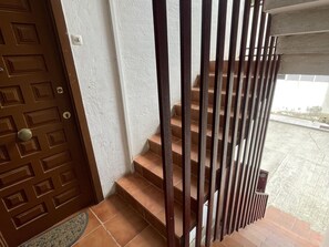 A brown door with a geometric pattern, a white wall, and a staircase with brown steps and metal railings. - Lodging in Miami Platja - 2 guests (Miami Playa)