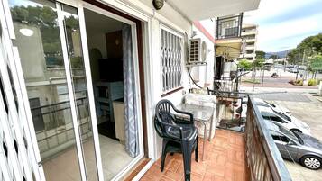 Een balkon met een schuifdeur, een tafeltje en een stoel.