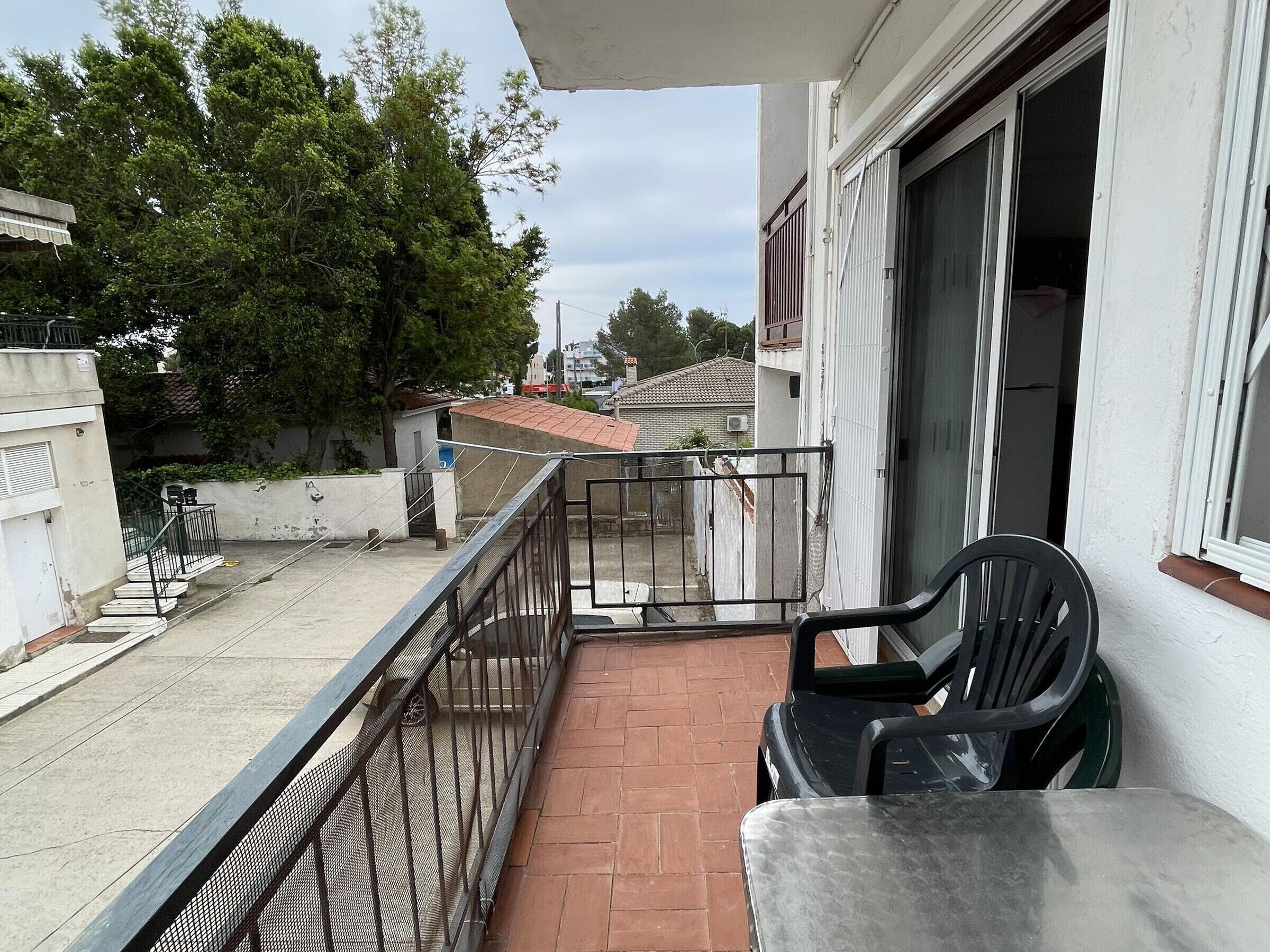 Een balkon met een stoel, een leuning en uitzicht op de straat en gebouwen.