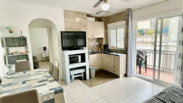 Een compacte leefruimte met een eethoek, kitchenette en een balkon met uitzicht.