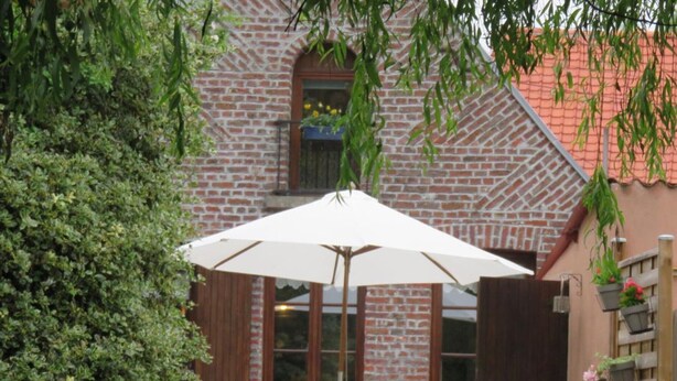 A brick building with a white umbrella, outdoor seating, and potted plants. - Charming house, pets welcome - 4 guests (PREMONT)