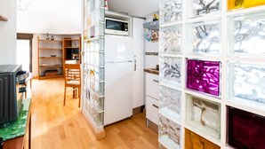 Eine kompakte Küche mit Mikrowelle, Kühlschrank und Vorratsschränken mit Glastüren.