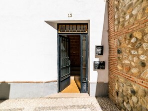 A narrow entrance with a black metal gate, a stone wall, and a number '12' on the wall. - Bright penthouse in city centre - 4 guests (Granada)
