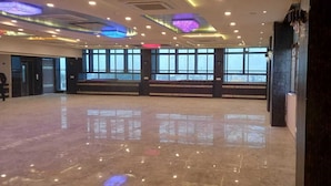Un vestíbulo amplio con piso pulido, ventanas grandes y una zona para escenario.