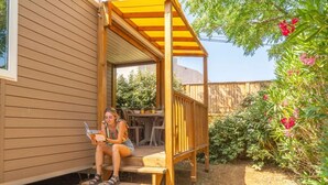 Une terrasse en bois dotée d’un espace salon couvert, d’une table et de chaises.
