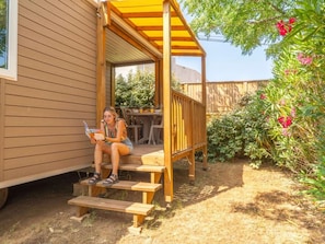 Eine Holzterrasse mit überdachter Sitzgruppe, einem Tisch und Stühlen.