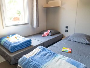 A room with two single beds, a window with curtains, and a small shelf with items. - Cottage with AC - 4 guests (Vic-la-Gardiole)