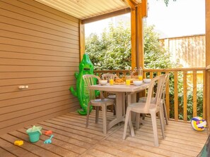 Eine Holzterrasse mit Tisch und Stühlen, einem grünen aufblasbaren Krokodil und einem Volleyball.