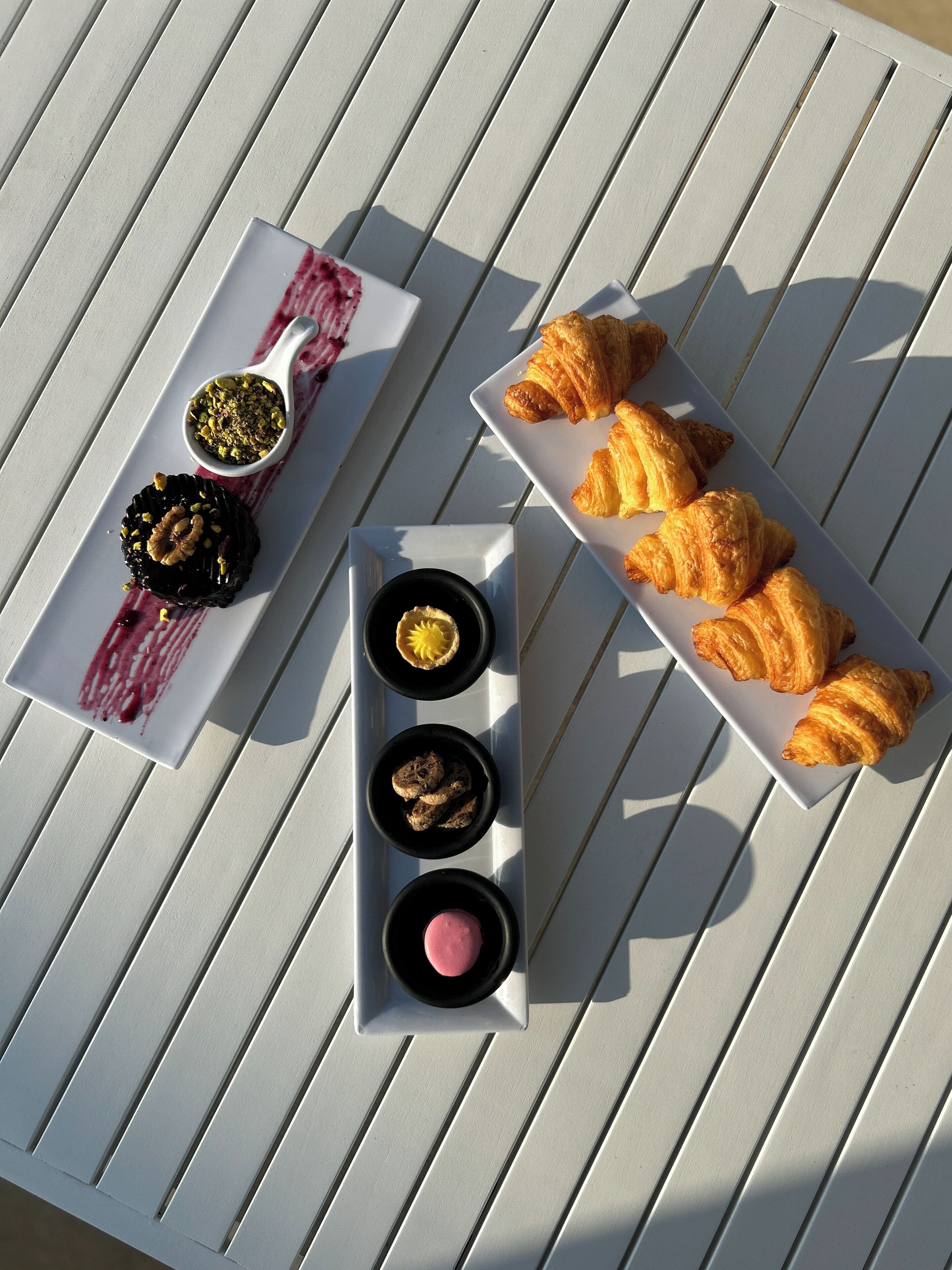 Ein weißer Tisch mit einem Streifenmuster, ein weißer Teller mit Gebäck und ein weißer Teller mit Desserts.