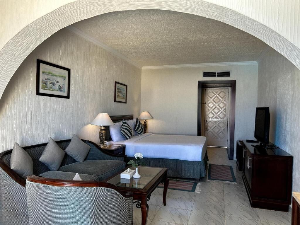 A hotel room with a bed, a sofa, a TV, and a desk.