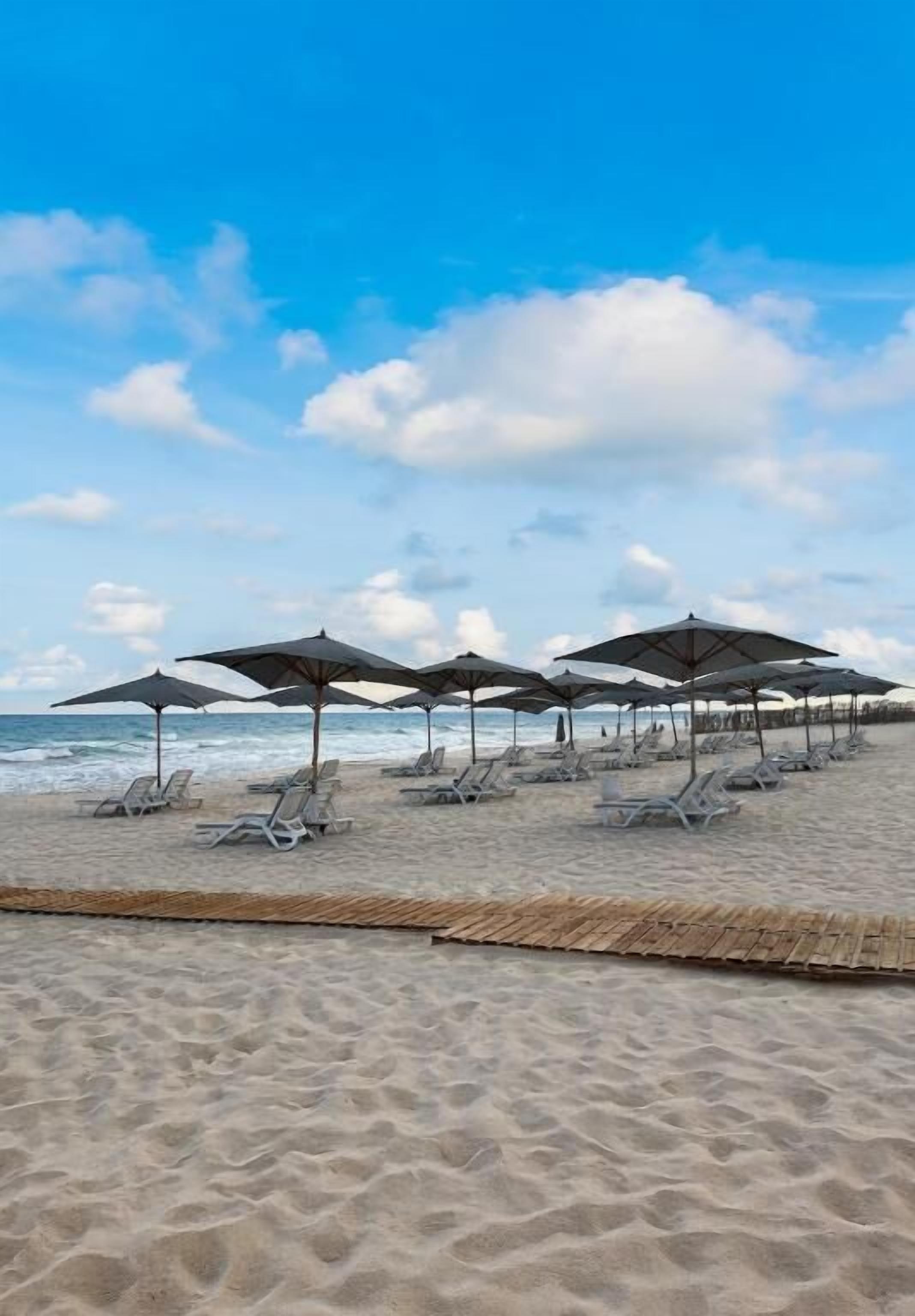 Uma praia com espreguiçadeiras e guarda-sóis.