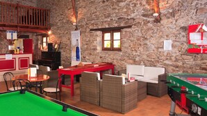 Un ambiente acogedor en el interior con mesa de billar, mobiliario de mimbre y mesa de futbolín.
