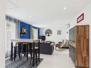 Ein moderner Wohnbereich mit Essbereich, einer Couch, einem Fernseher und einem Holzkabinett.