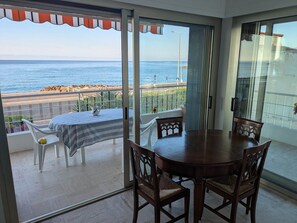 A balcony with a table and chairs, a view of the sea, and a glass door leading to the interior. - Pleasant apartment sea view - 4 guests (Menton)