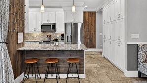 A modern kitchen with white cabinets, a granite island, and bar stools. - New! Private Pool -Free Golf Cart -Block to Beach -Fully Updated -Crystal Beach (Destin)