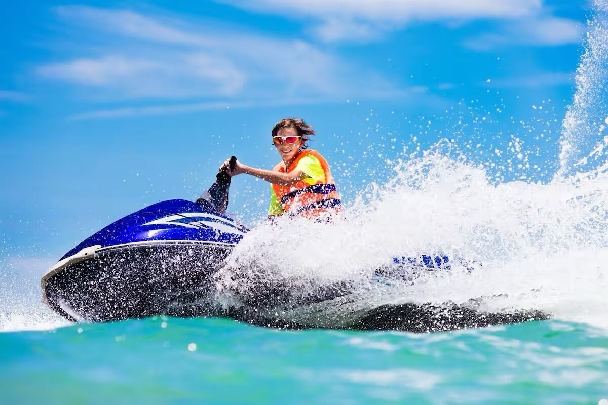Une personne sur un jet ski, avec de l’eau qui éclabousse tout autour.