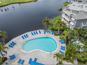 A swimming pool with blue lounge chairs and a view of a body of water.