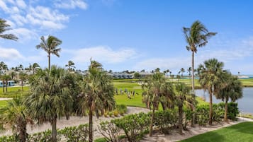 A golf course with a water body, palm trees, and a clubhouse.