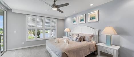 A bedroom with a bed, two bedside tables, a ceiling fan, and a window with blinds.