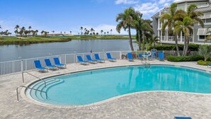 A swimming pool with blue chairs and a water view.